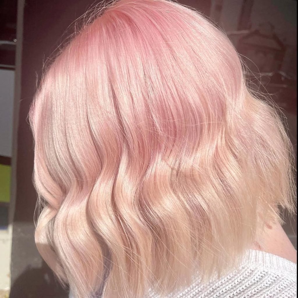 close-up view of textured wavy pastel pink bob hair with golden blonde highlights