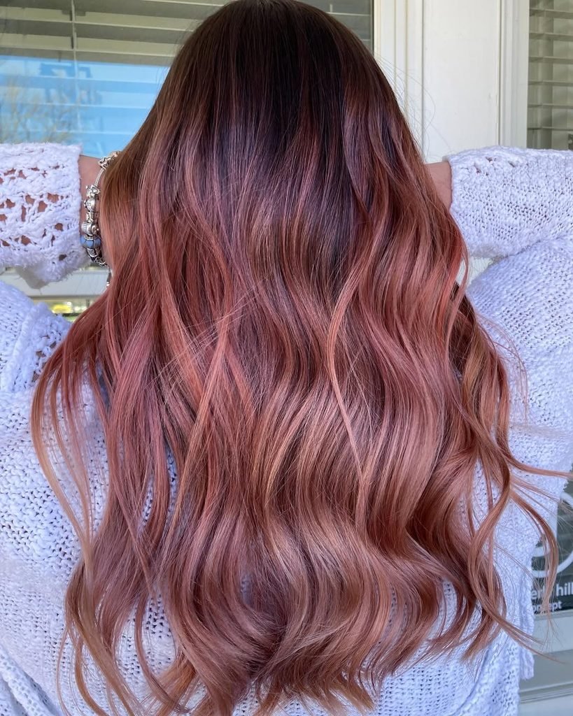 back view of long wavy hair with a blended rose gold copper balayage