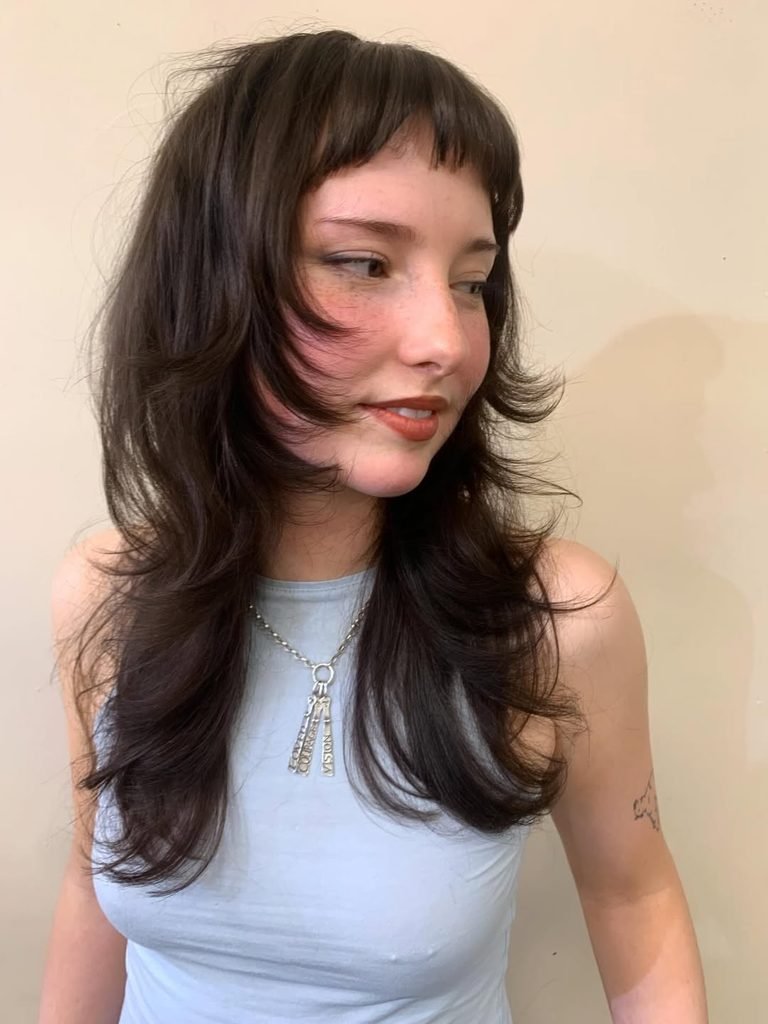 woman with dark brown layered shag haircut and short textured bangs