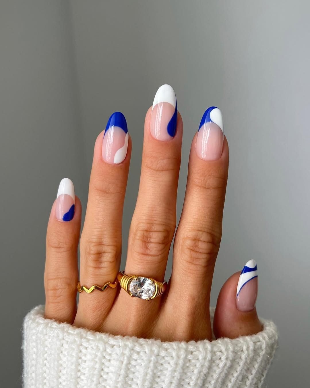 almond shaped manicured nails with minimalist blue and white wavy abstract line art