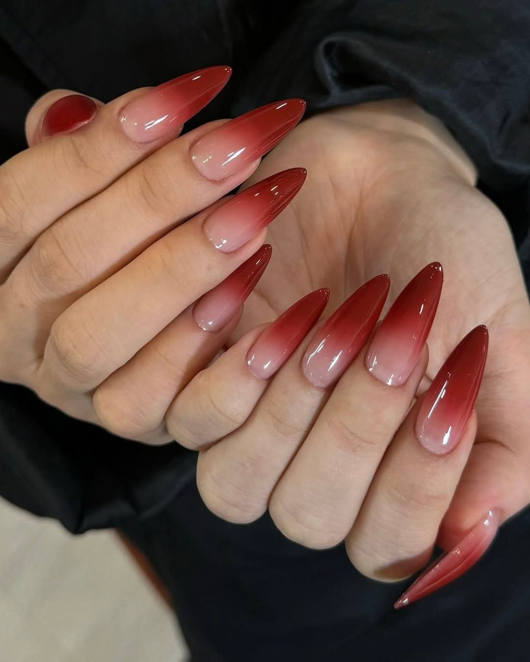 long almond shaped manicured nails with a red and nude ombre gradient design