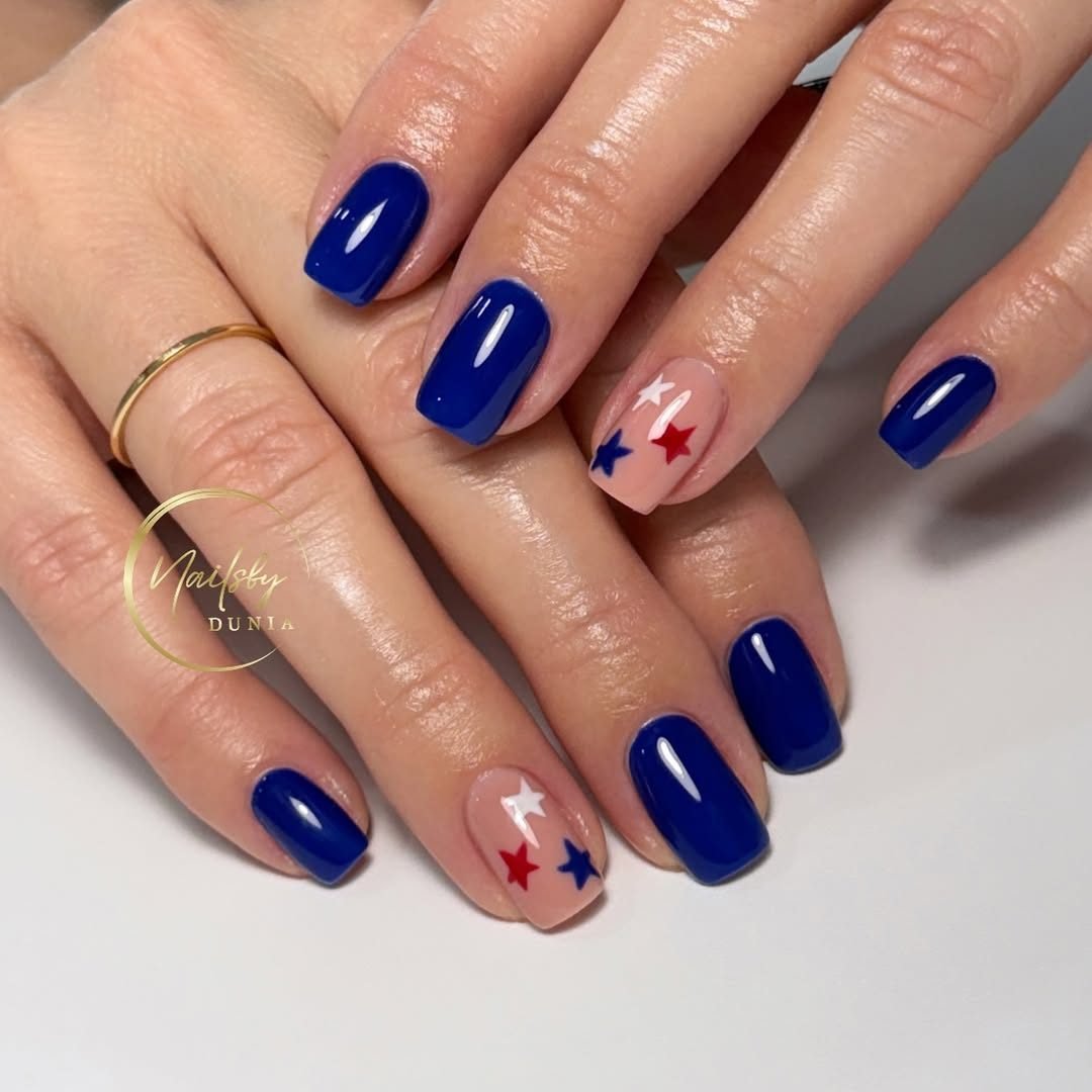 glossy royal blue manicured nails with red, white, and blue star accent art