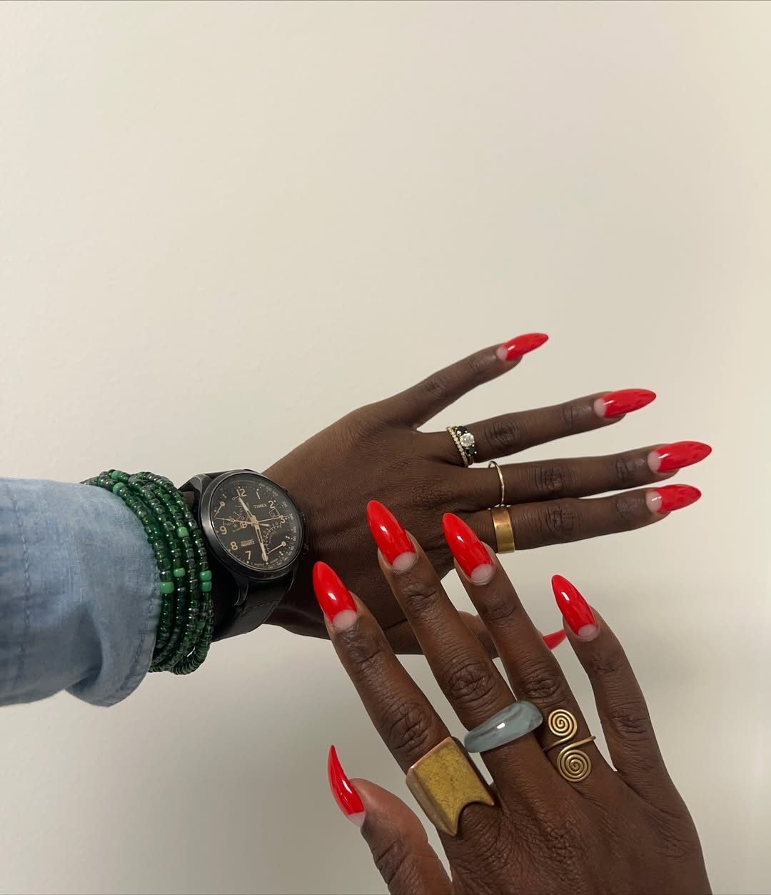 vibrant red almond shaped manicured nails with a cutout half moon design on dark skin