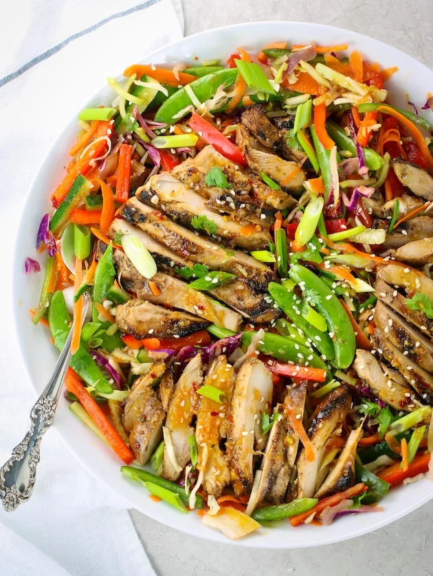 sliced grilled chicken breast served over a vibrant asian slaw with edamame and sesame seeds