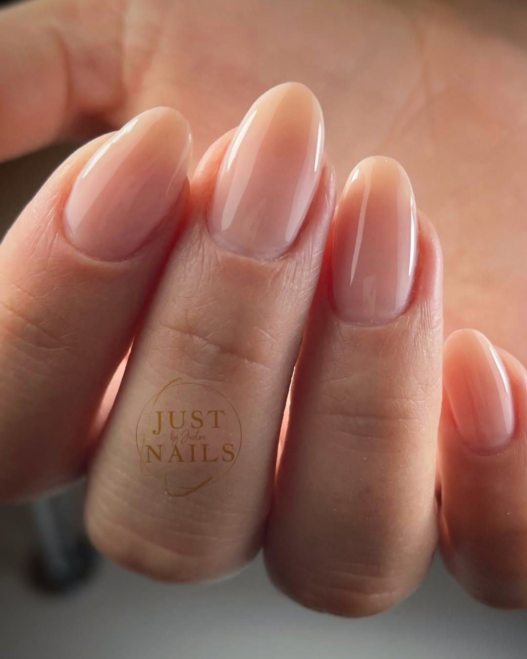closeup of a glossy nude gel manicure on long oval shaped nails
