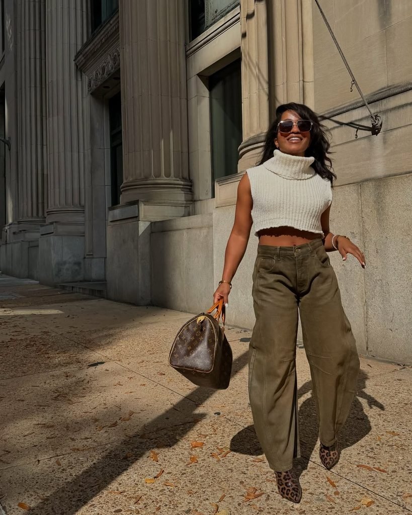 woman in cropped cream sweater and olive green wide leg pants walking outside