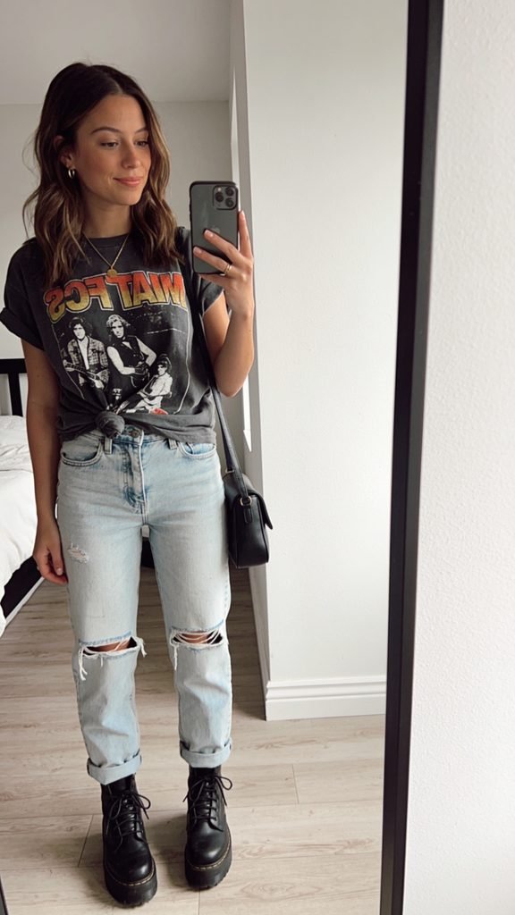 woman wearing graphic t-shirt and ripped light wash jeans in a mirror selfie