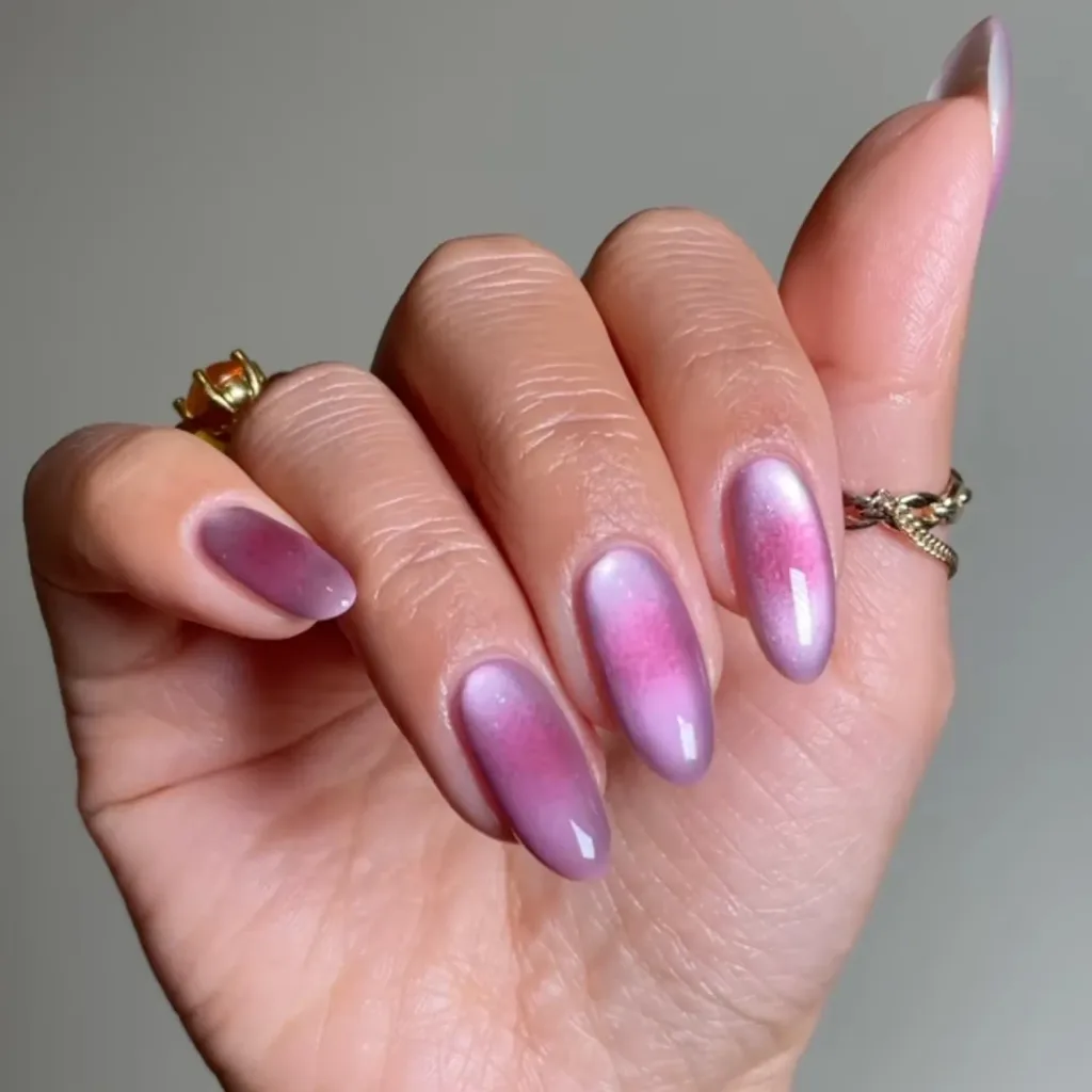 pink aura magnetic cat eye nails on almond shape manicured hand