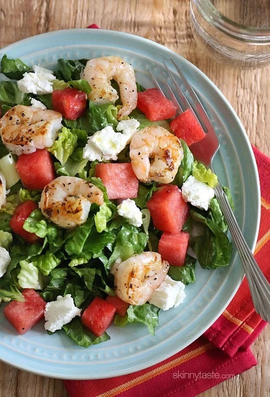 grilled shrimp and watermelon salad with feta cheese and mixed greens on a blue plate
