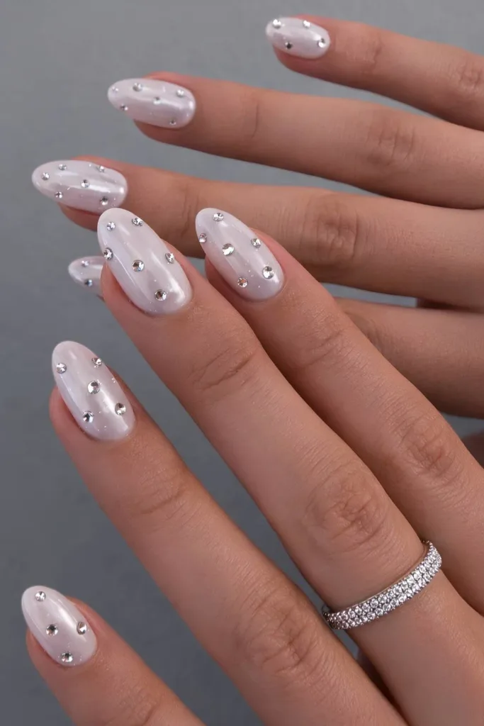 oval soft white pearl chrome nails embellished with small reflective rhinestones