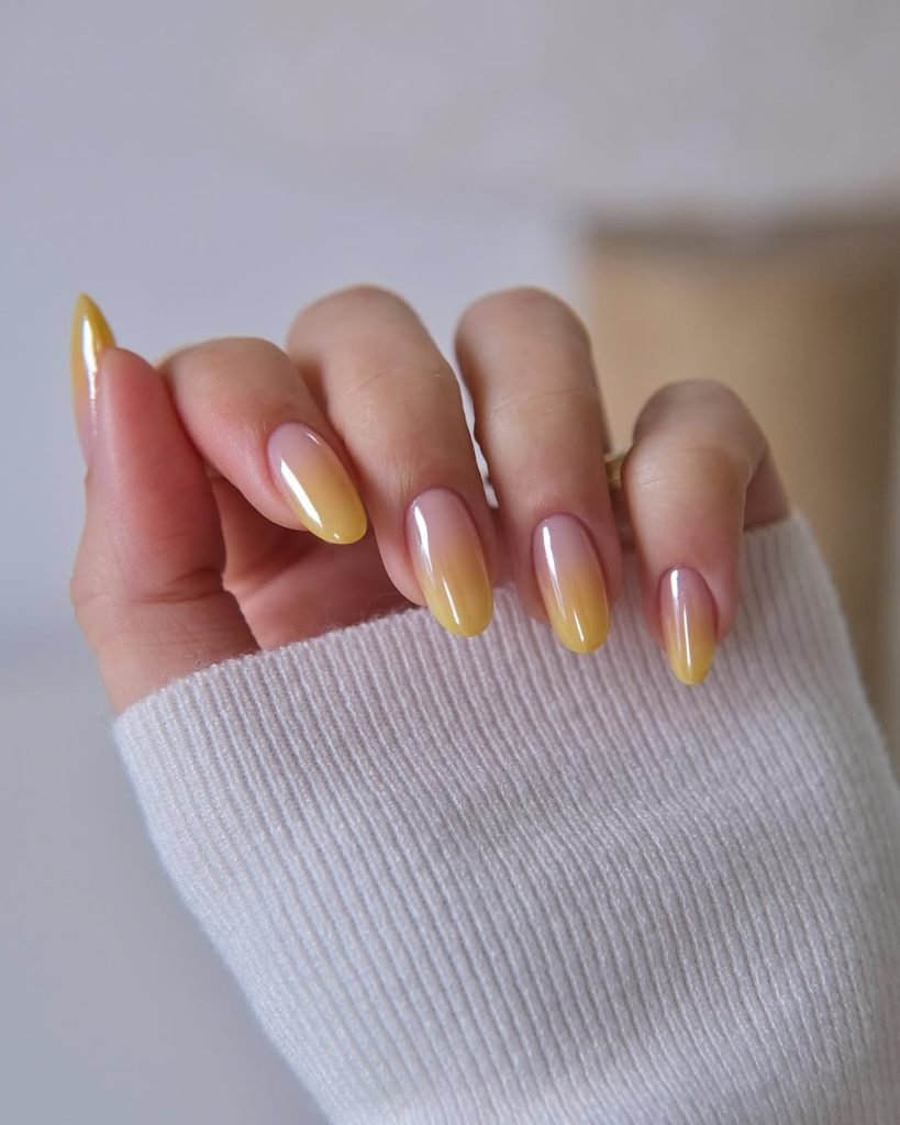 oval nails with a glossy peach to yellow ombre chrome finish