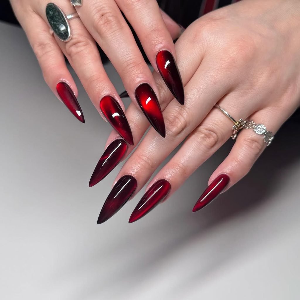 long stiletto nails with a glossy deep red cat eye magnetic finish