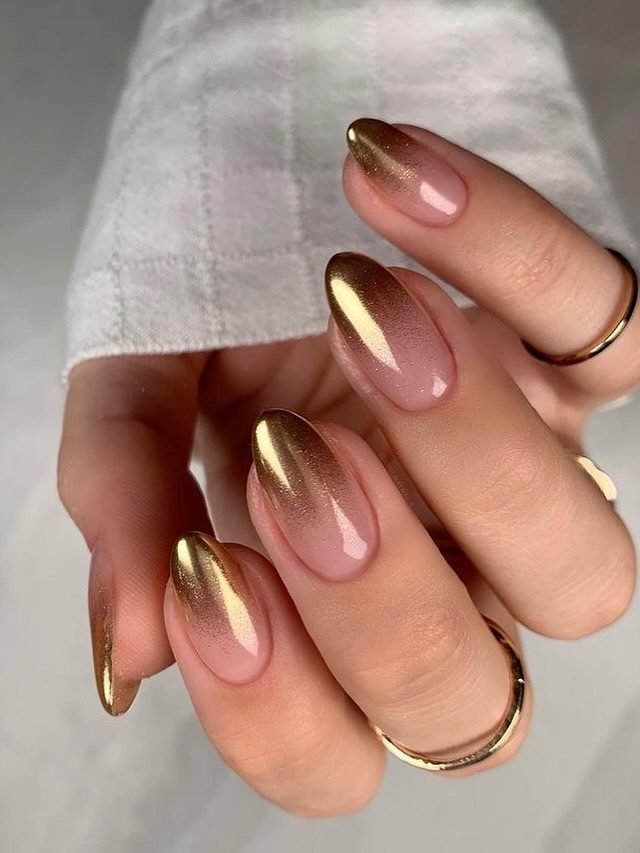oval manicured nails featuring a glossy gold chrome ombre gradient on a nude base