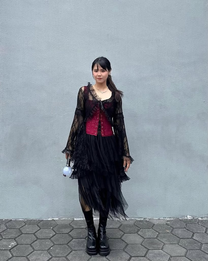 woman in red corset, black lace cardigan, and black tulle skirt