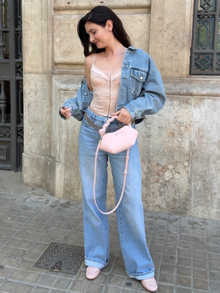 woman in pink corset top, oversized denim jacket, and wide leg jeans