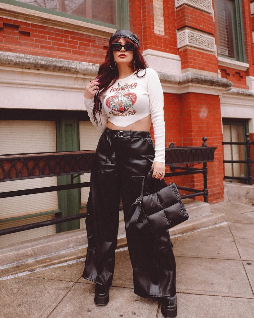 woman in graphic crop top, black faux leather pants, and a beret