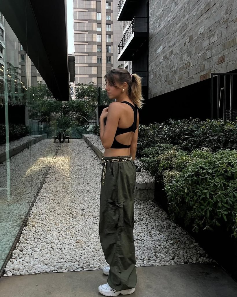 woman in black cutout crop top, olive green cargo pants, and sneakers