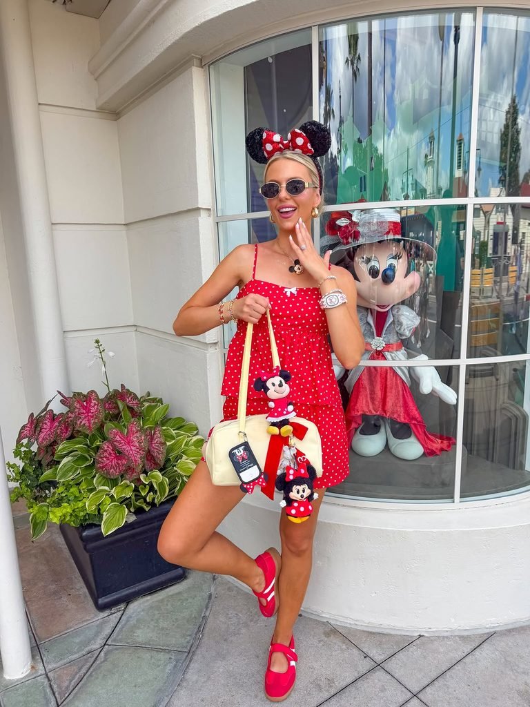woman in a red and white polka dot dress posing outside a shop window