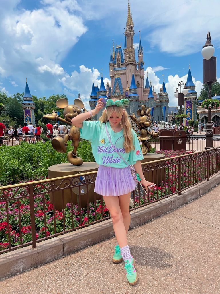 woman in a mint green tee and purple skirt before a castle