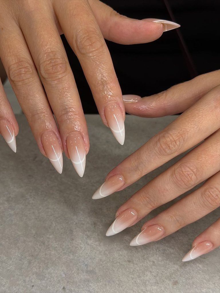 long stiletto gel nails featuring a modern nude and white ombre french tip