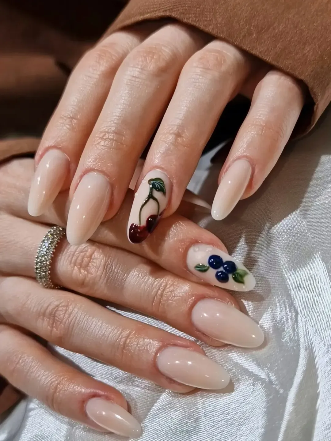 light nude almond nails featuring 3d cherry and blueberry fruit nail art designs