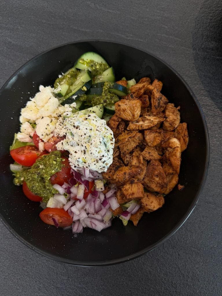 grilled chicken bowl with diced red onions, cucumbers, tomatoes, feta, and tzatziki sauce