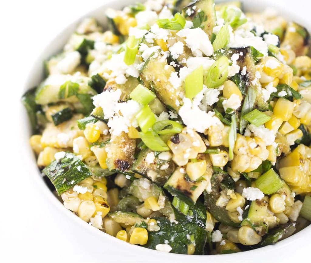 grilled corn and zucchini salad topped with crumbled feta cheese and chopped green onions