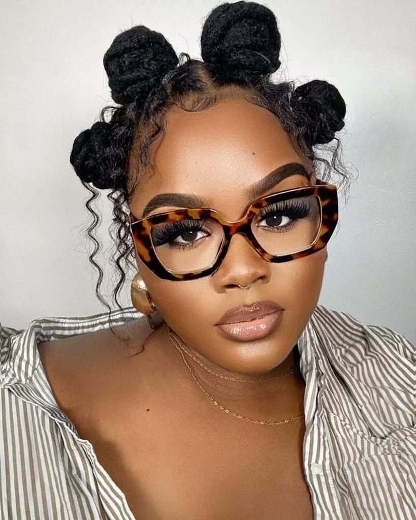 woman wearing glasses with her hair styled in multiple small space buns
