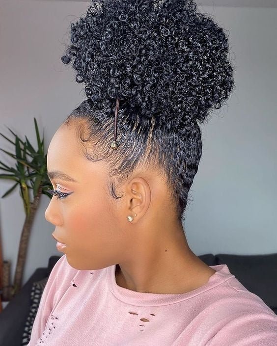 woman in profile showing a high curly puff hairstyle with sleeked edges
