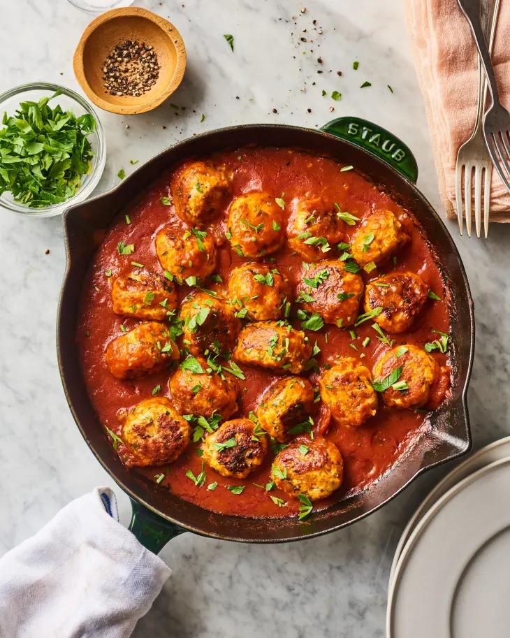 savory turkey meatballs simmering in tomato marinara sauce garnished with fresh chopped parsley