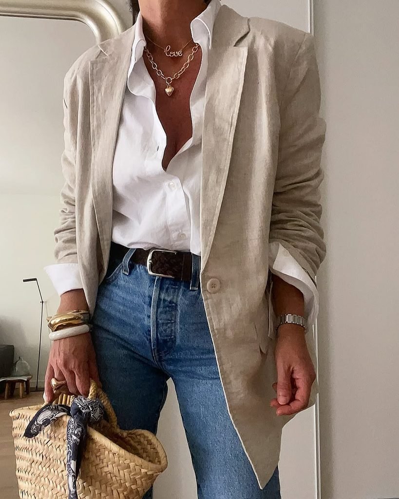 close-up of a person wearing a beige blazer, white shirt, and blue jeans