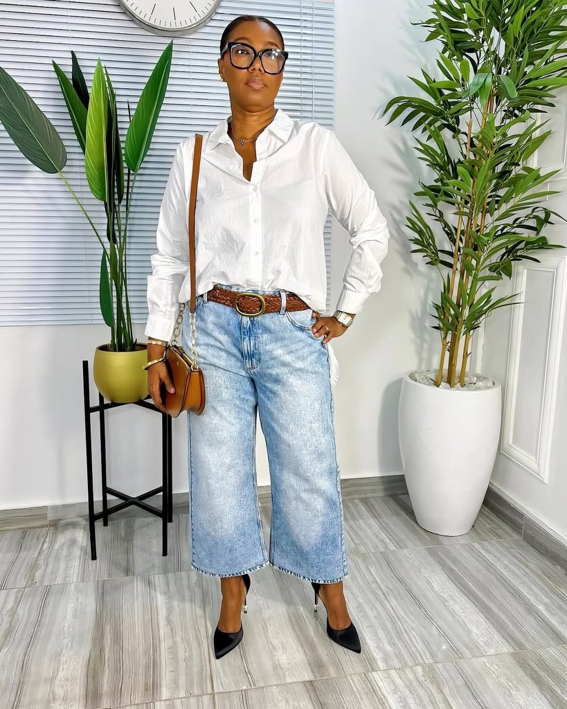 woman wearing a white button-down shirt, wide-leg cropped jeans, and black high heels