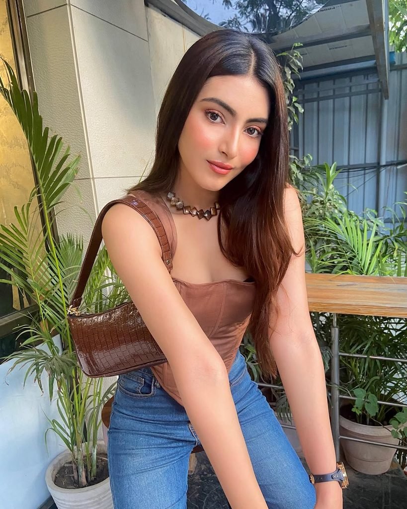 woman wearing a brown corset top and blue jeans while holding a shoulder bag