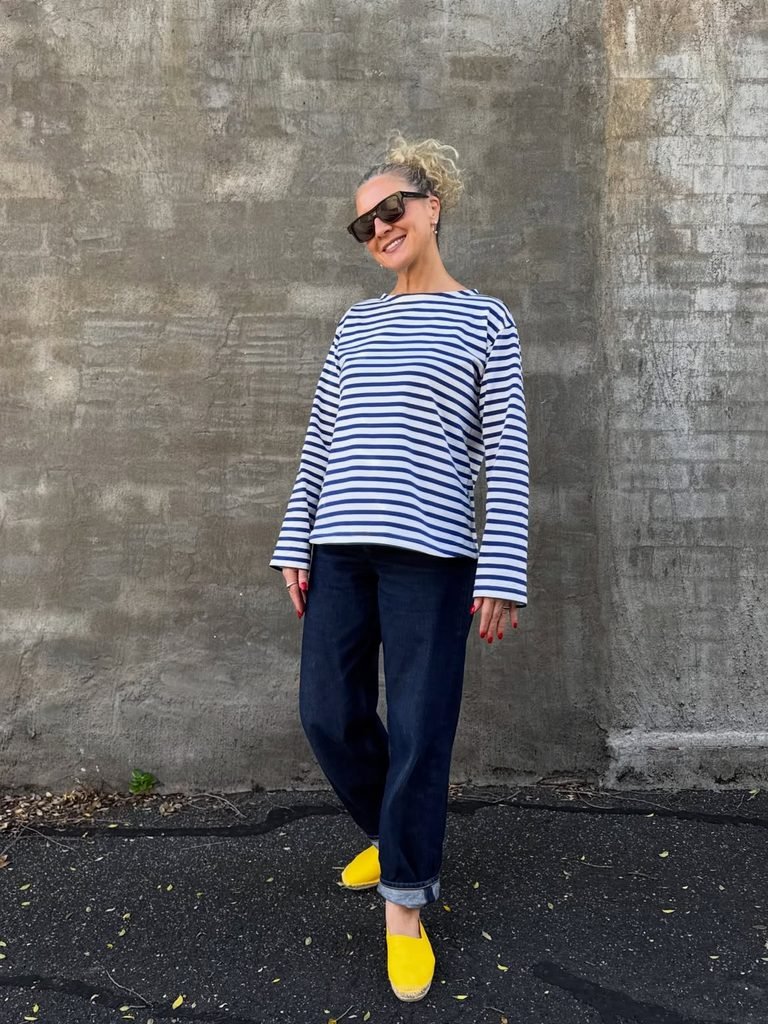 woman wearing a striped long sleeve shirt, dark cuffed jeans, and bright yellow shoes