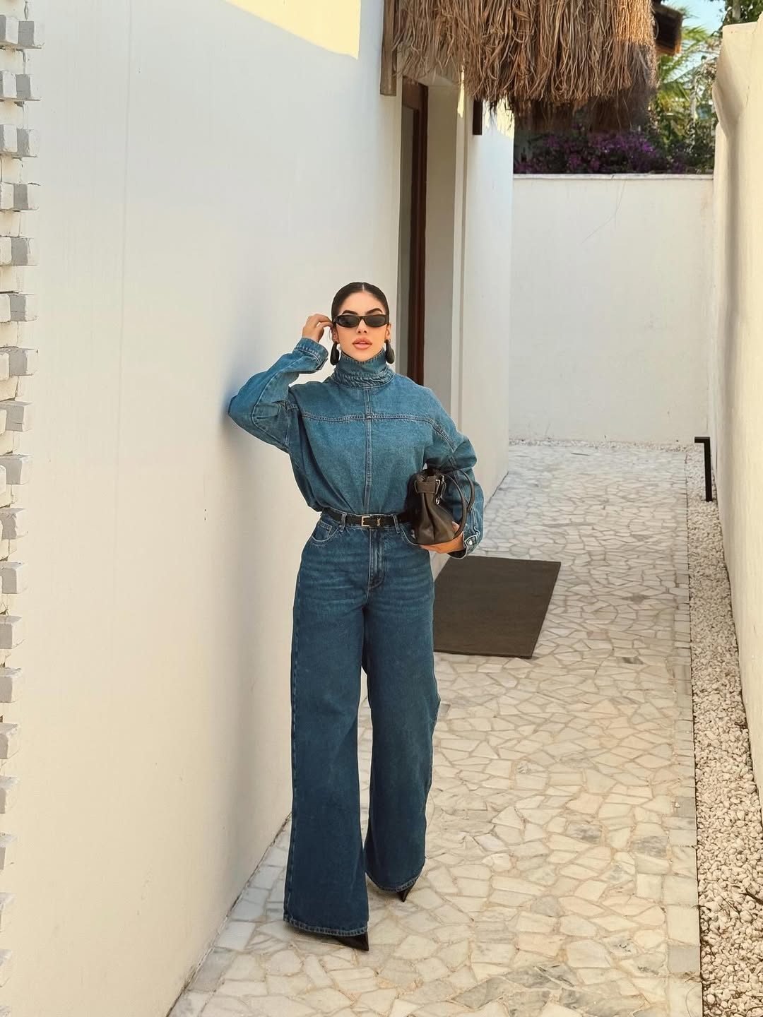 woman posing in denim shirt and wide leg jeans on a stone walkway