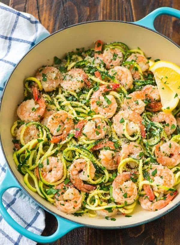 garlic shrimp scampi with zucchini noodles and a lemon wedge in a blue skillet