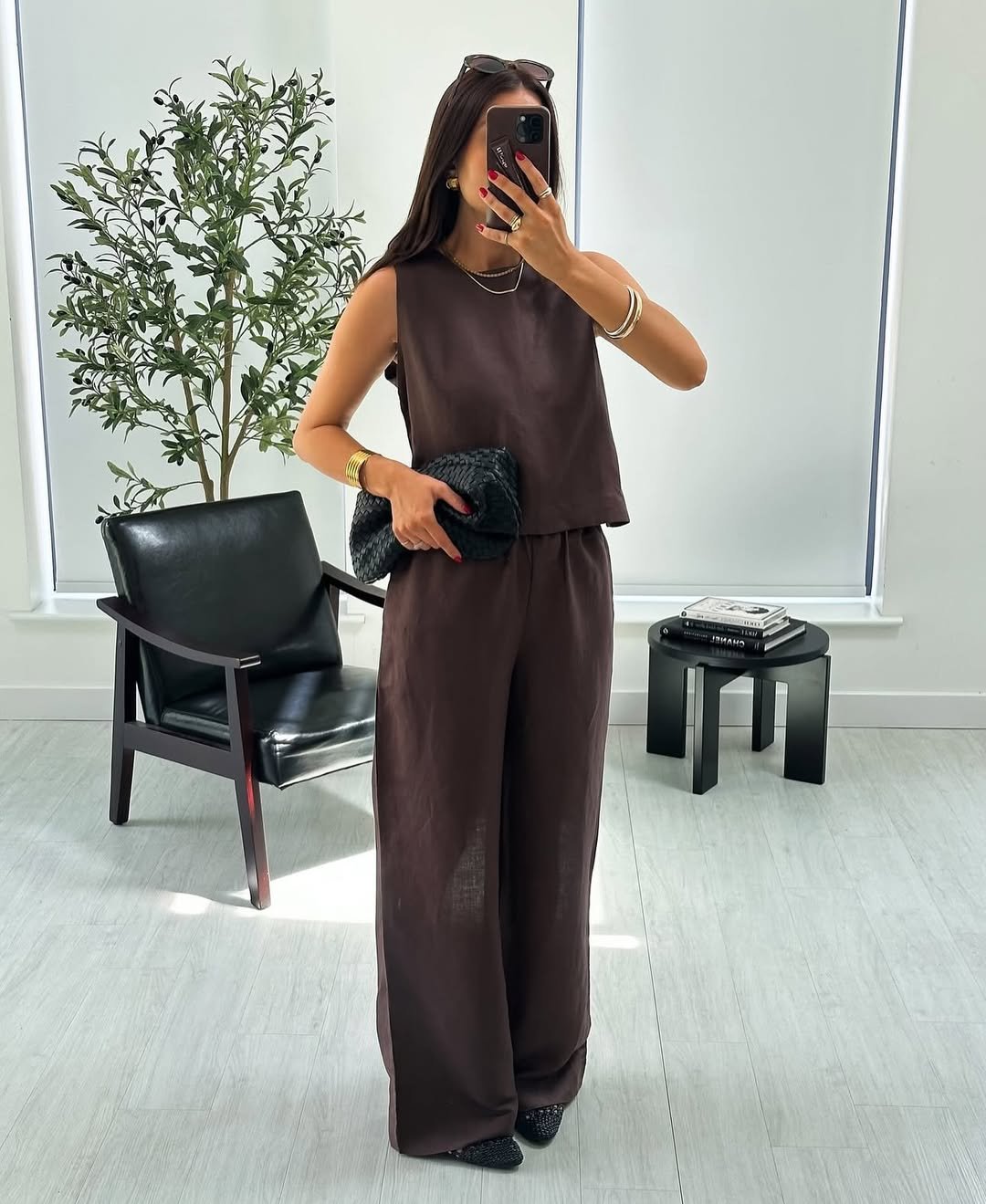 woman wearing sleeveless brown top and matching wide leg trousers taking mirror selfie
