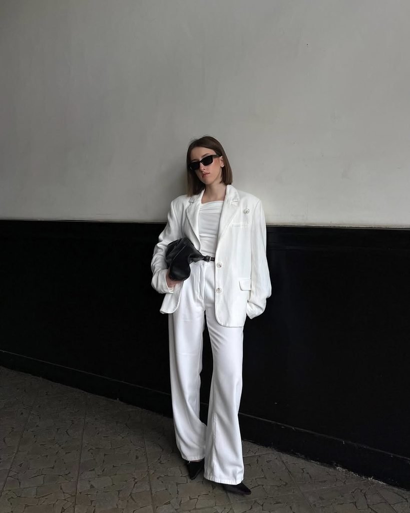 woman wearing white linen blazer and matching white wide leg pants against a wall