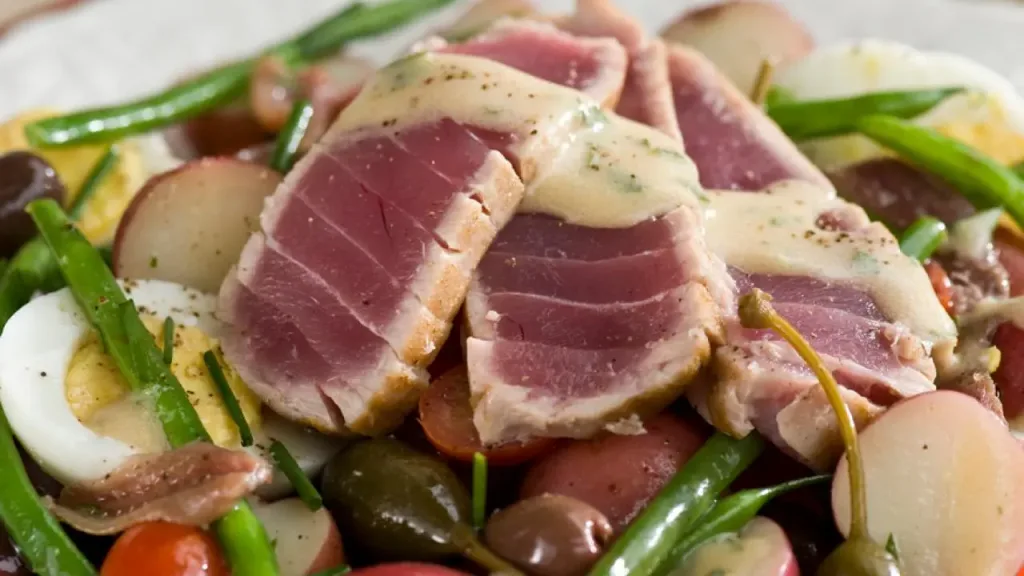 seared tuna slices arranged over a niçoise salad with green beans and potatoes