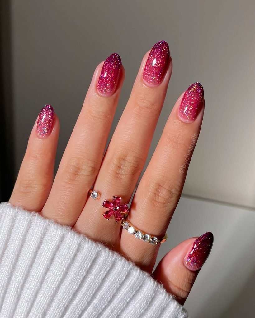 sparkly magenta glitter ombre nails with gold flower and gemstone rings