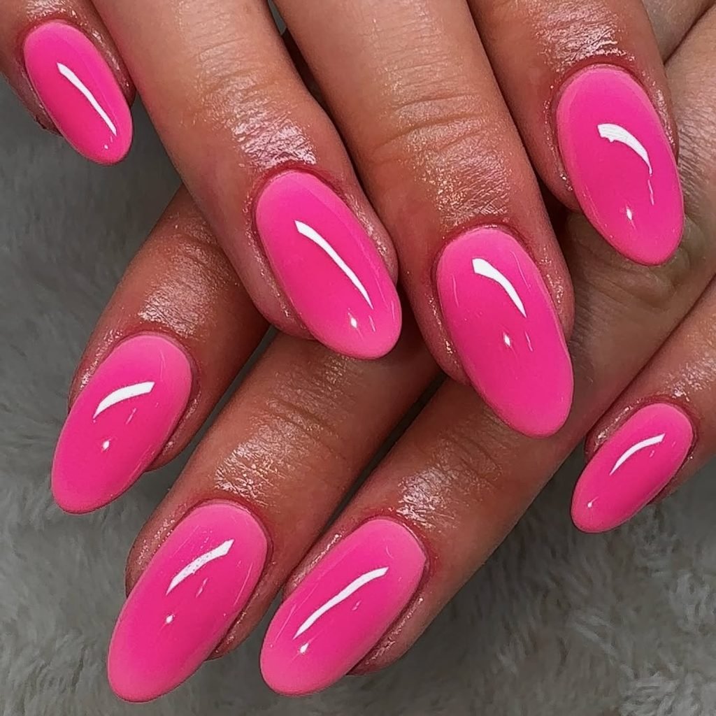 glossy bright hot pink manicured oval nails close up on overlapping hands