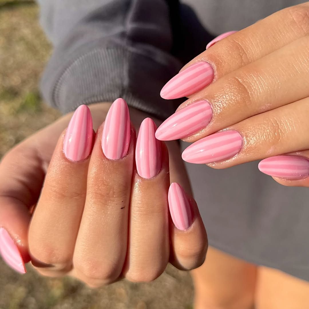 almond shaped manicured nails featuring a light and dark pink vertical stripe design