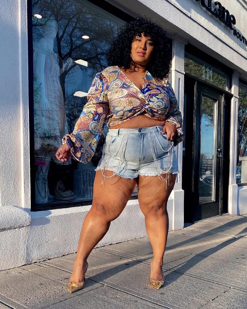 woman wearing a paisley print wrap top and denim shorts with chain detailing