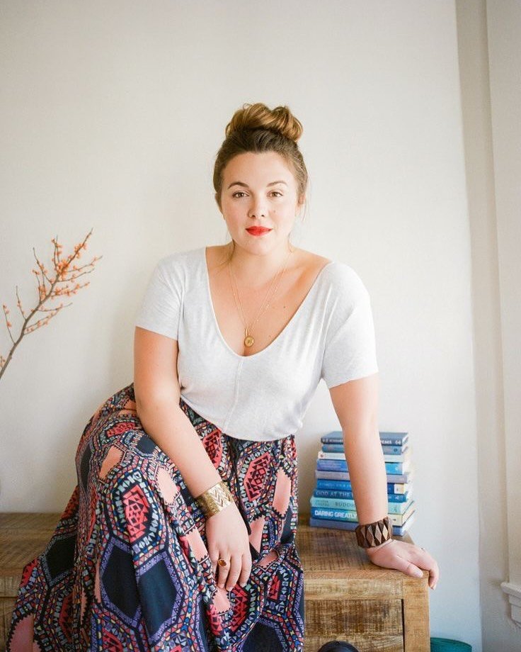 woman with a hair bun wearing a white v-neck shirt and patterned maxi skirt