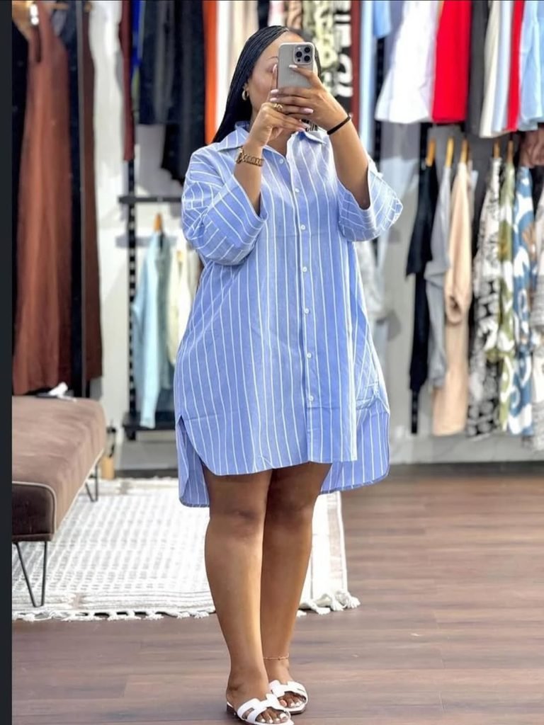 woman in a blue and white striped shirt dress taking a mirror selfie
