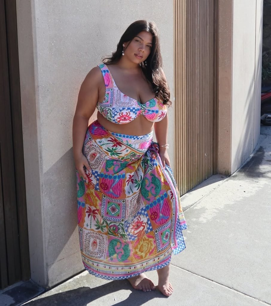 woman leaning against a wall wearing a colorful patterned bikini and matching sarong