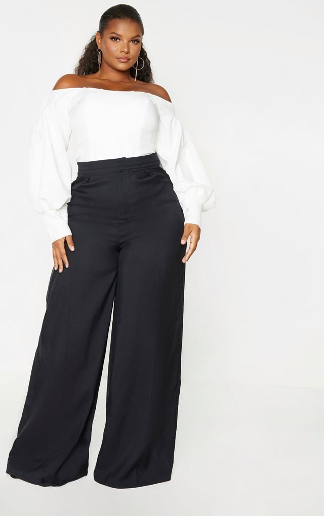 woman wearing a white off-the-shoulder blouse and black wide-leg trousers