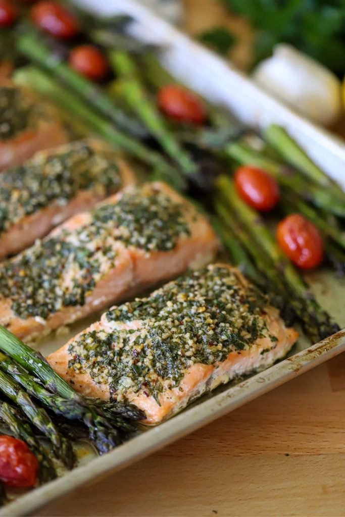 sheet pan salmon fillets topped with herb crust next to roasted asparagus and tomatoes