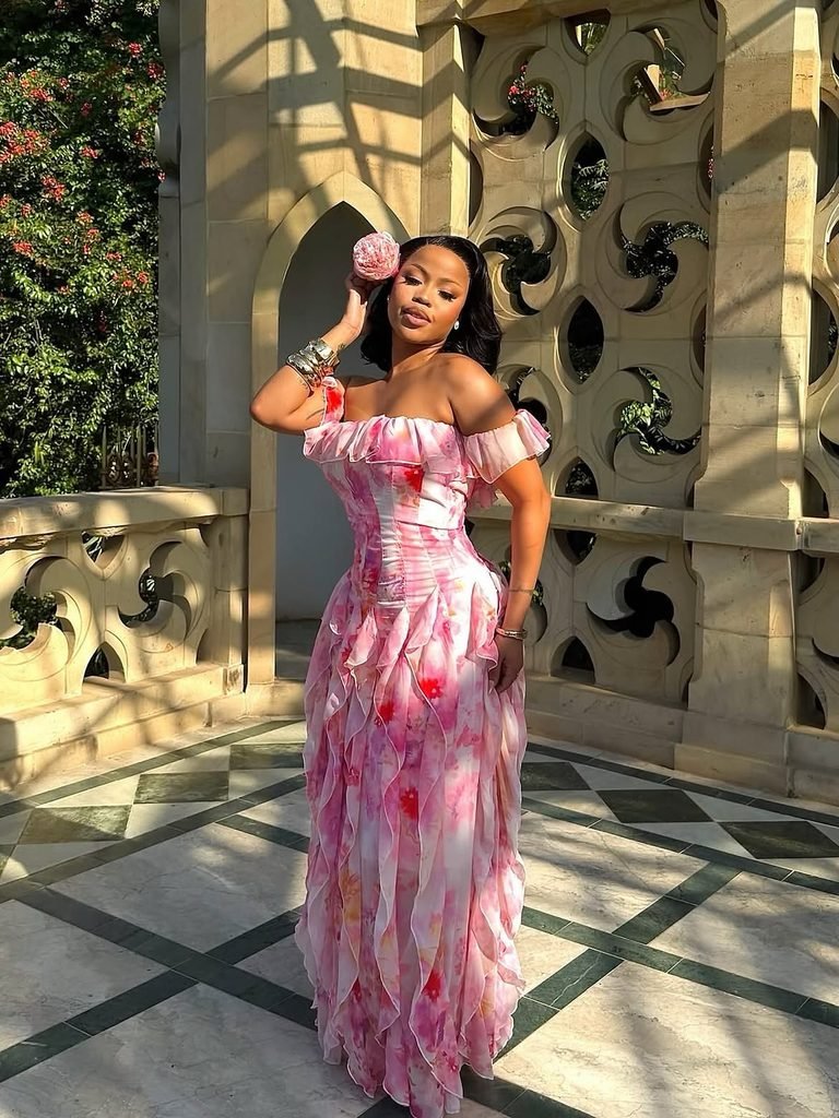 woman wearing elegant pink floral ruffled maxi dress posing by stone columns