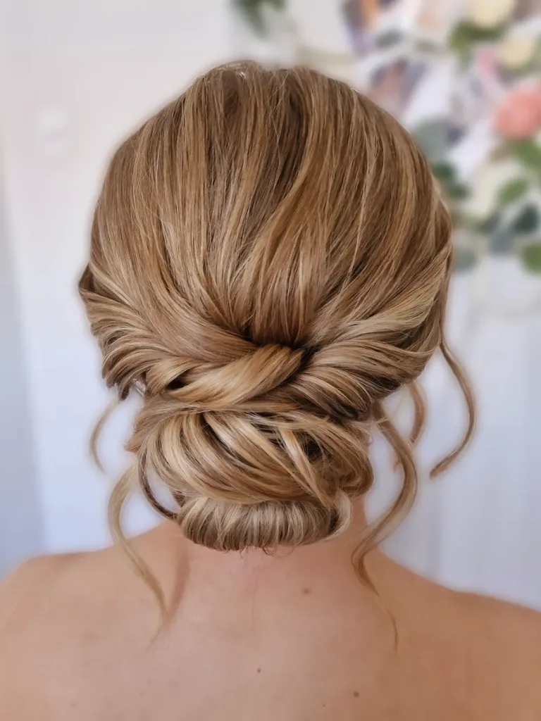 back view of an elegant twisted low chignon summer hairstyle with face-framing tendrils